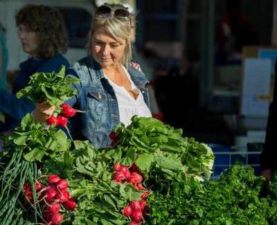 Woman at Market looking at fresh produce - radishes and lettuce
